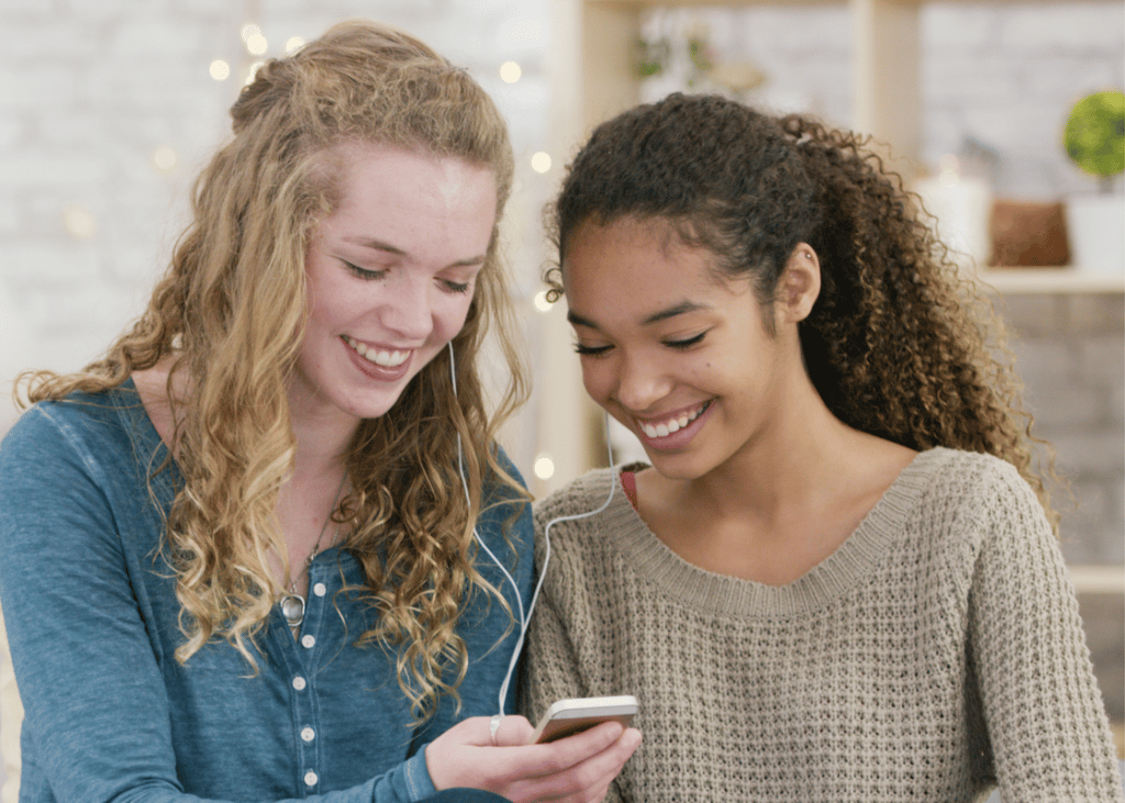 Two girls listening to music together on a smart phone