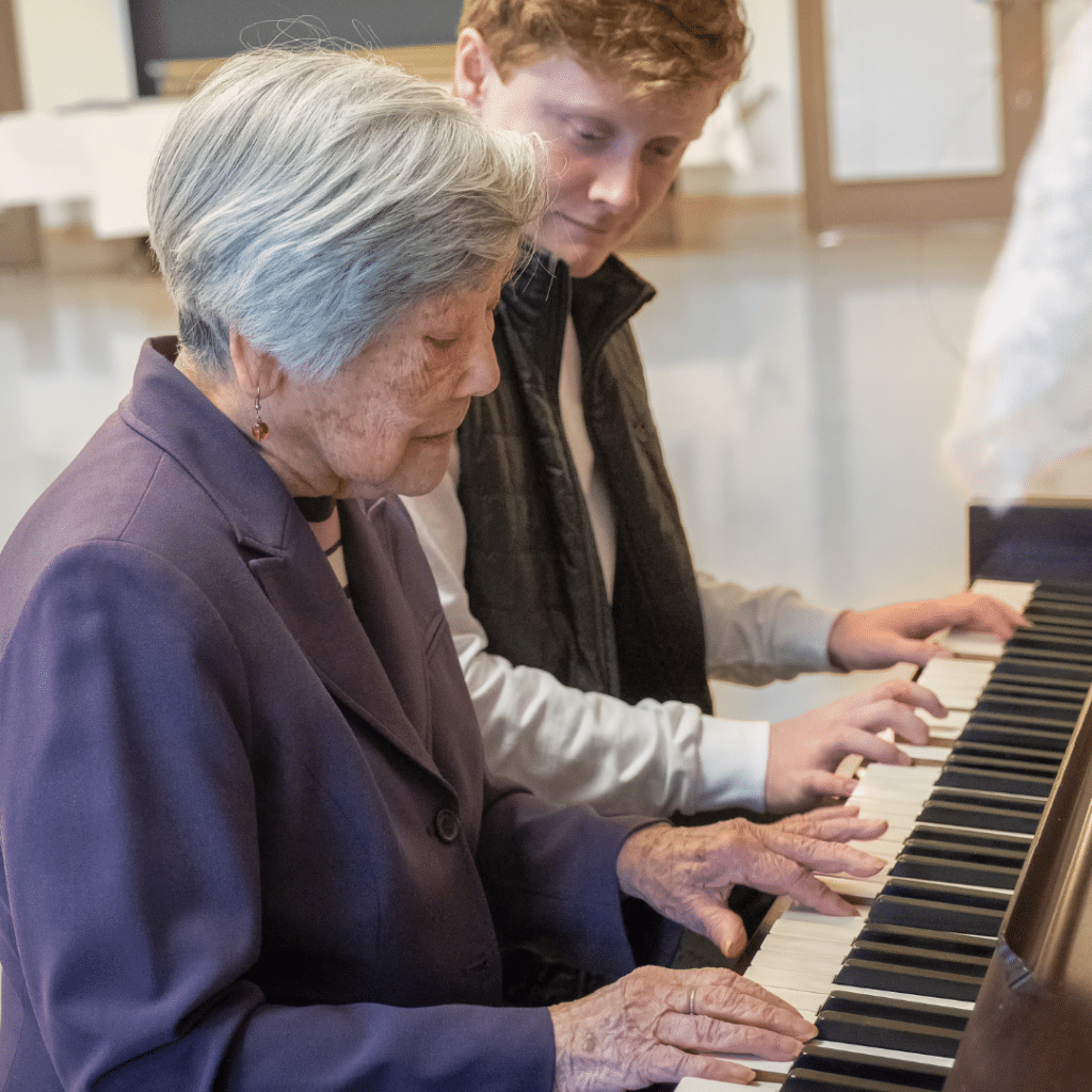 Older pianist playing along with younger pianist